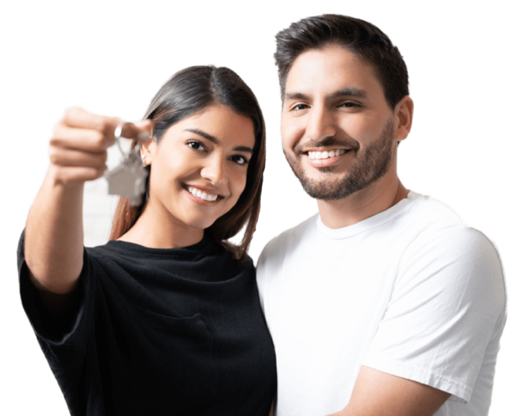 Smiling man embracing girlfriend holding new house key while standing in living room